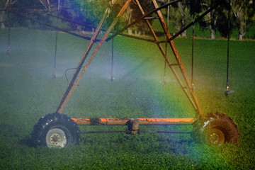 Sprinklers Irrigating Crop Field Farming Grains Lush Green with Rainbow from Misty water spray