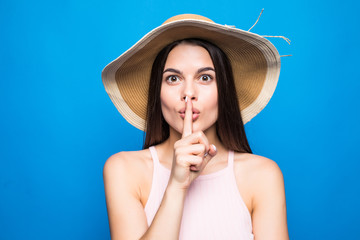 Portrait closeup of woman wearing straw hat showing finger at lips to keep secret isolated over...