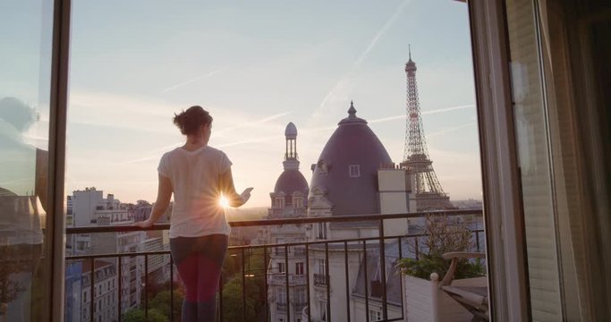 happy woman using smartphone taking photo enjoying sharing summer vacation experience in paris photographing beautiful sunset view of eiffel tower on balcony