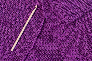 Baby purple cardigan, crocheted close-up and wooden hook