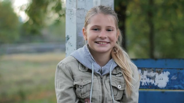 Portrait of blonde preteen girl smiling and laughing at camera in suburbs