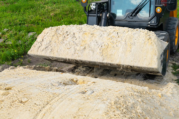 The loader took the sand into the bucket for construction work.