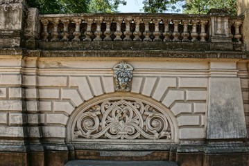 part of an old concrete fence with a pattern and a lion's head on the street