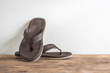 Men sandals footware brown on wood grunge table desk.