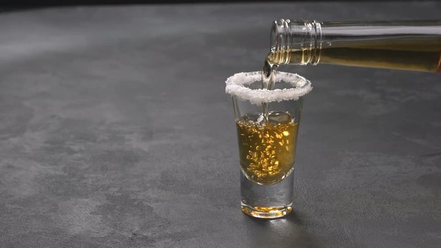 Pouring gold tequila on a black background ,selective focus