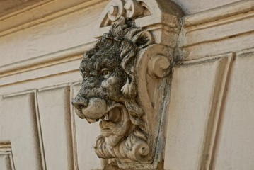 part of the old brown concrete wall of the fence with a sculpture of the head of a lion