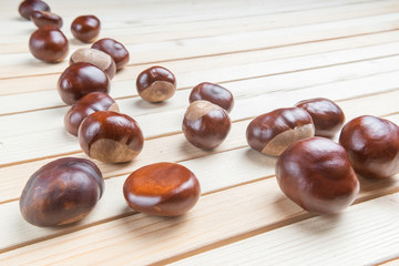 Fresh chestnut fruit scattered on light wood table