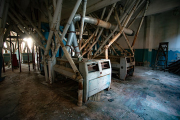 Abandoned flour milling factory. Old rusty roller mill equipment with pipeline
