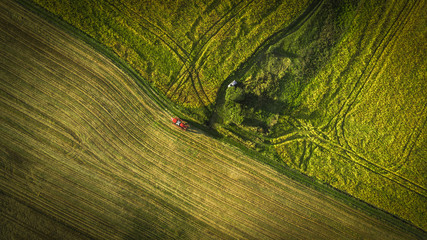 Aerial shot of tractor on the agricultural field sowing. Red tractors working on the agricultural field with sprayer.