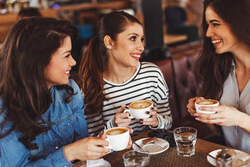 Three young women enjoy coffee at a coffee shop