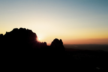 Aerial view of a spectacular sunset behind some rocky mountains in Sardinia, Italy.