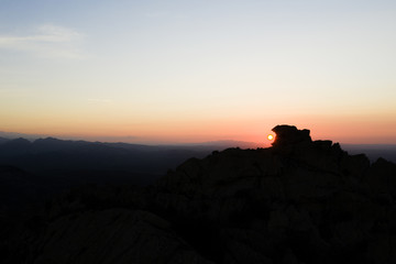 Aerial view of a spectacular sunset behind some rocky mountains in Sardinia, Italy.