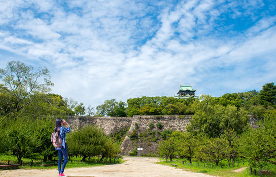 Beautiful women with backpacks is taking photos in Osaka Castle.