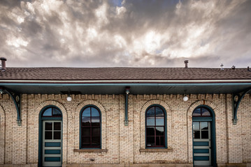 Exterior of one story brick building with clouds in the sky above.