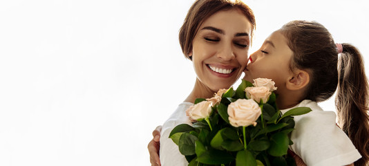 Family. Love. Holiday. Mom and daughter. Girl is giving a bouquet for her mother and kissing her,...