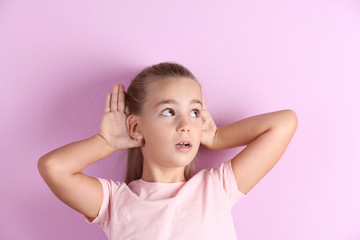 Cute little girl with hearing problem on color background