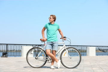 Handsome young man with bicycle outdoors on sunny day