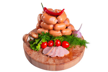 Sausages on a wooden round board with greens tomatoes and pepper. Sausages on a white isolated background