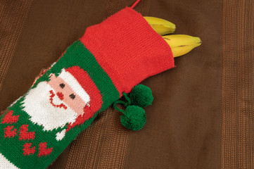 Colorful christmas sock with drawing of Santa Claus filled with bananas. Gift concept for child who has been bad, healthy gift, improvise a present...