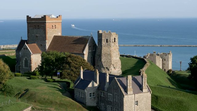 igh angle view of historic Dover Church and ancient Roman lighthouse as a far-distant ferry leaves the harbor at Dover bound for for France.