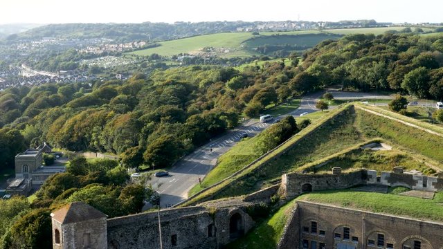 High Angle-Traffic flows flows around the bend of Harold's Road where it becomes Godwin Road below the verdant walls of the Dover Castle on the coast of England at the Dover Straits.