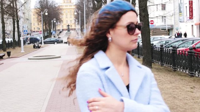 young long-haired woman walks through the city in a blue beret and coat in cold weather