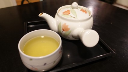 Close up Glass of water on the wooden table with blurry background hand of asian woman in cafe restaurant 