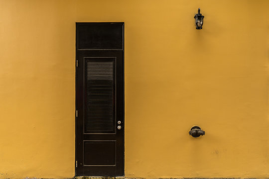 Facade With A Black Stylish Door With Yellow Wall With Anti Fire Hydraulic System And A Lamp