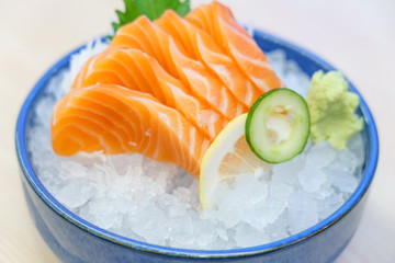 Salmon sashimi on ice serve with fresh wasabi and carrot slide, Japanese food style. Top view with copy space and text