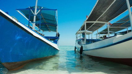 a traditional boat close up anchored in beach seashore with transparent clear sea