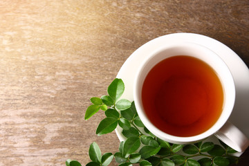 Herbal tea in hot white glass With leaves on its side And put on the wooden floor.