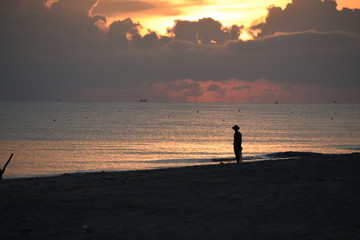 Contemplation at the beautiful sunset.Silhouette of the young man on the beach