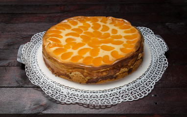 Schmandkuchen mit Mandarinen auf Mahagoni Holzuntergrund.