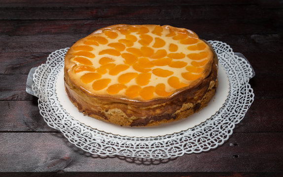 Schmandkuchen mit Mandarinen auf Mahagoni Holzuntergrund.
