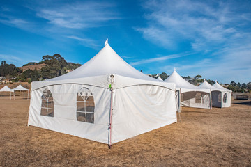 White tent in brown grass field under blue sky © Frank Fennema