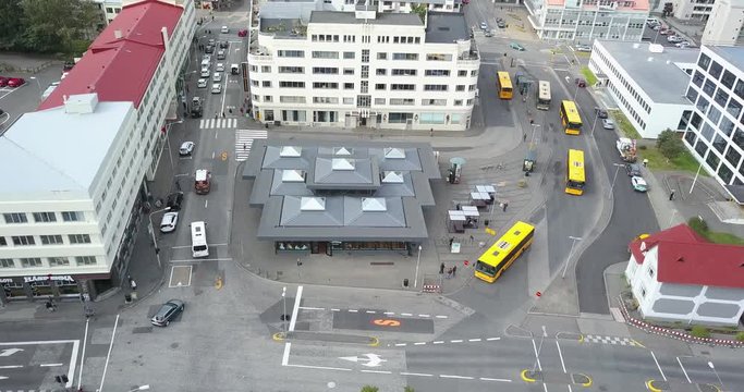 Bus station in Reykjavik. Three yellow buses arrive and leave.