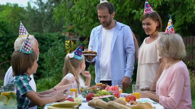 Caring parents bringing cake with candles, celebrating birthday of daughter