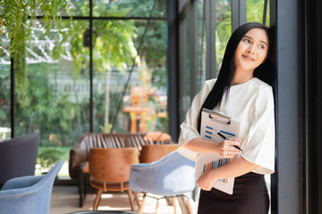 Young businesswoman standing with document near the office window, business concept