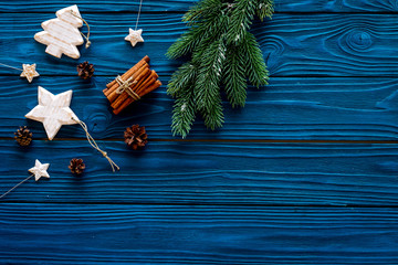 Spruce branch, cones and vintage toys in shape of spruce and stars on blue background for decoration on chrismas or new year top view copy space