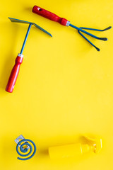 Mosquito protection for garden. Mosquito coil and spray near garden tools on yellow background top view copy space