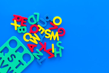 Alphabet for kids concept. English letters in disorder near stencil on blue background top view copy space