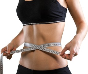 Female fitness model holding a tape measurer around her waist -