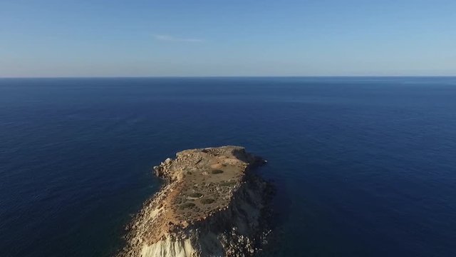 Aerial drone shot flying over the uninhabited island of Yeronisos Sacred Holy Island off the coast of Cyprus with the vast blue sea in the background