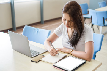 Young asian female college working with laptop, blank white screen digital tablet.