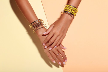 Female hands with bracelets and rings on colorful background