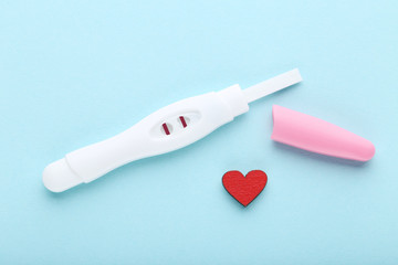 Pregnancy test with red heart on blue background