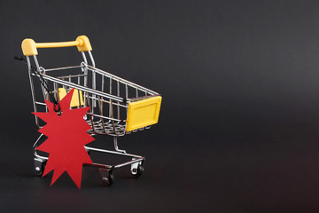 Red sale tag with shopping cart on black background