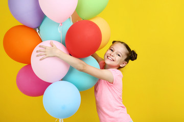 Fototapeta na wymiar Beautiful young girl with colored balloons on yellow background