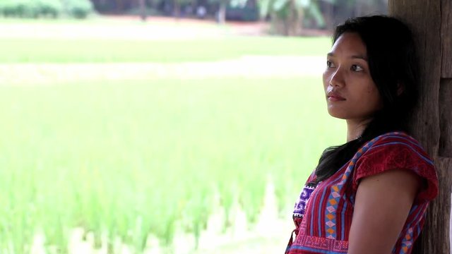 A girl in traditional dress Karen ethnicity sitting in a paddy field