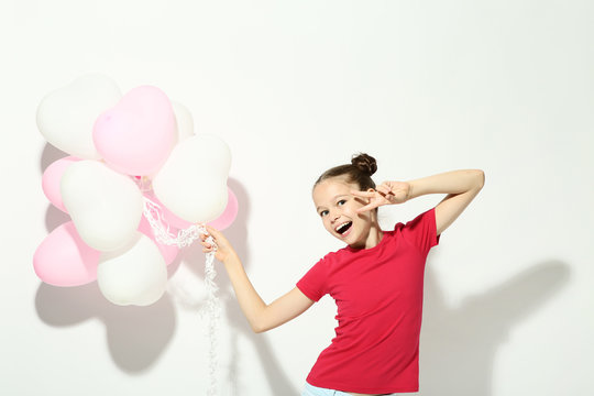 Beautiful young girl with balloons on white background
